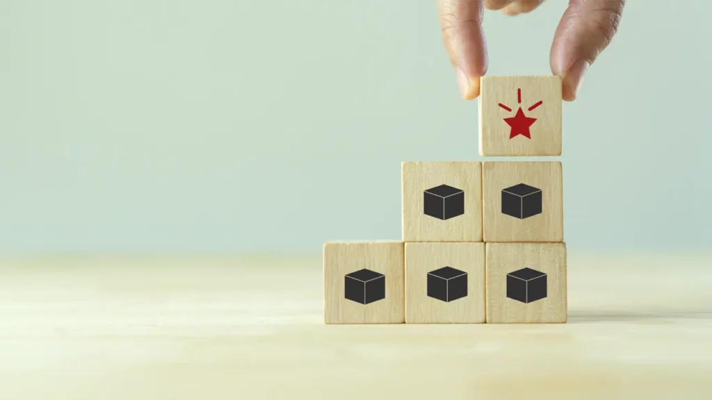 A person stacking a bunch of wooden cubes to make a staircase which symbolizes progress.