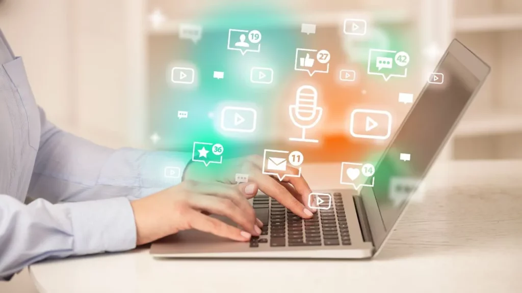 Person typing on laptop with social media notification icons floating above.