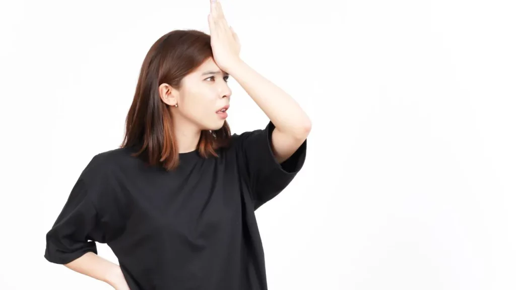 Woman in black shirt with hand on forehead, looking exasperated.