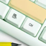 Macro shot of a white computer keyboard with the Enter/Return key highlighted in beige.