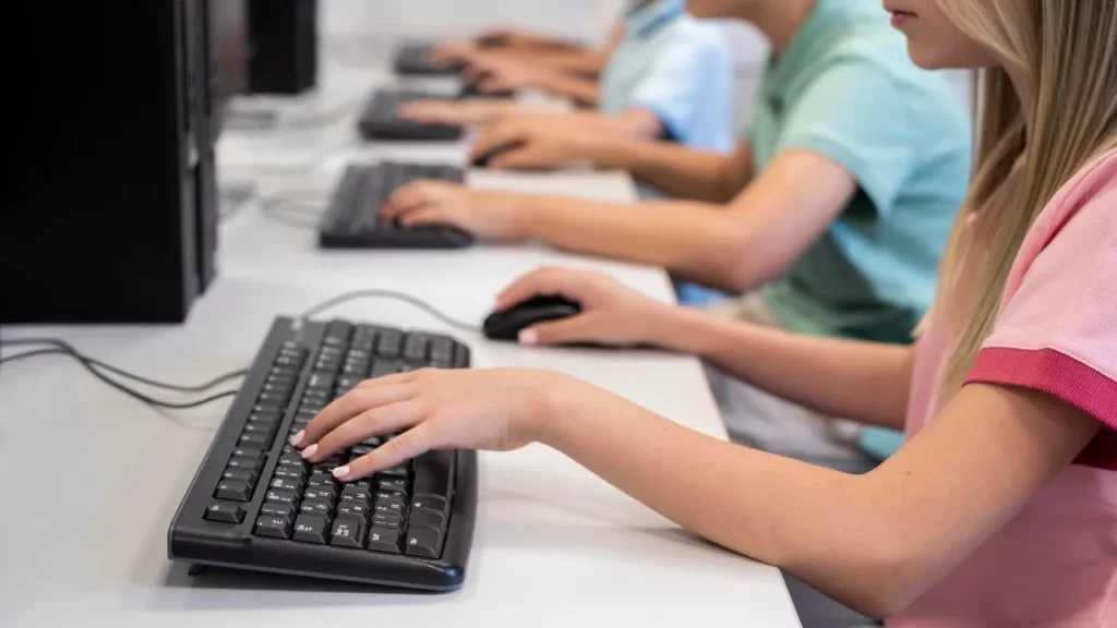 Students typing on desktop computers in a computer lab.