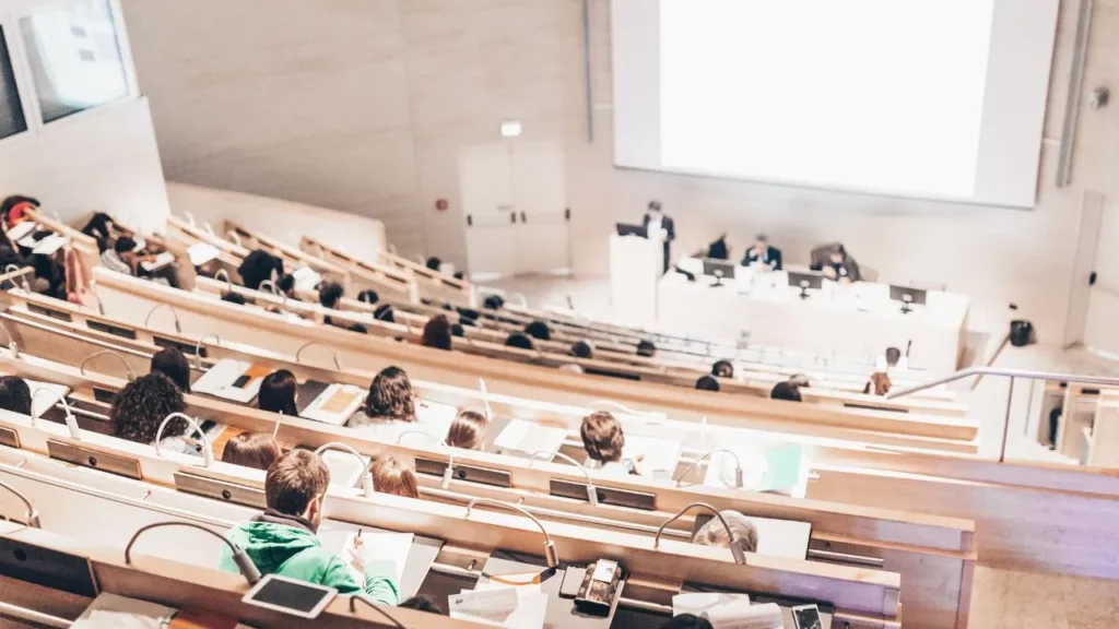 Large university lecture hall with many students watching a presentation on the big screen.