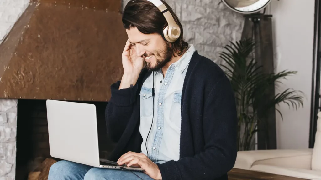 A man listening to AI voices on his laptop.