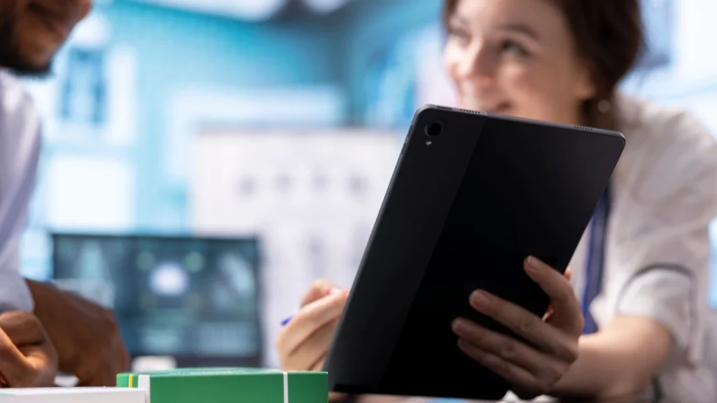 A woman holding a tablet during a discussion in a professional setting.