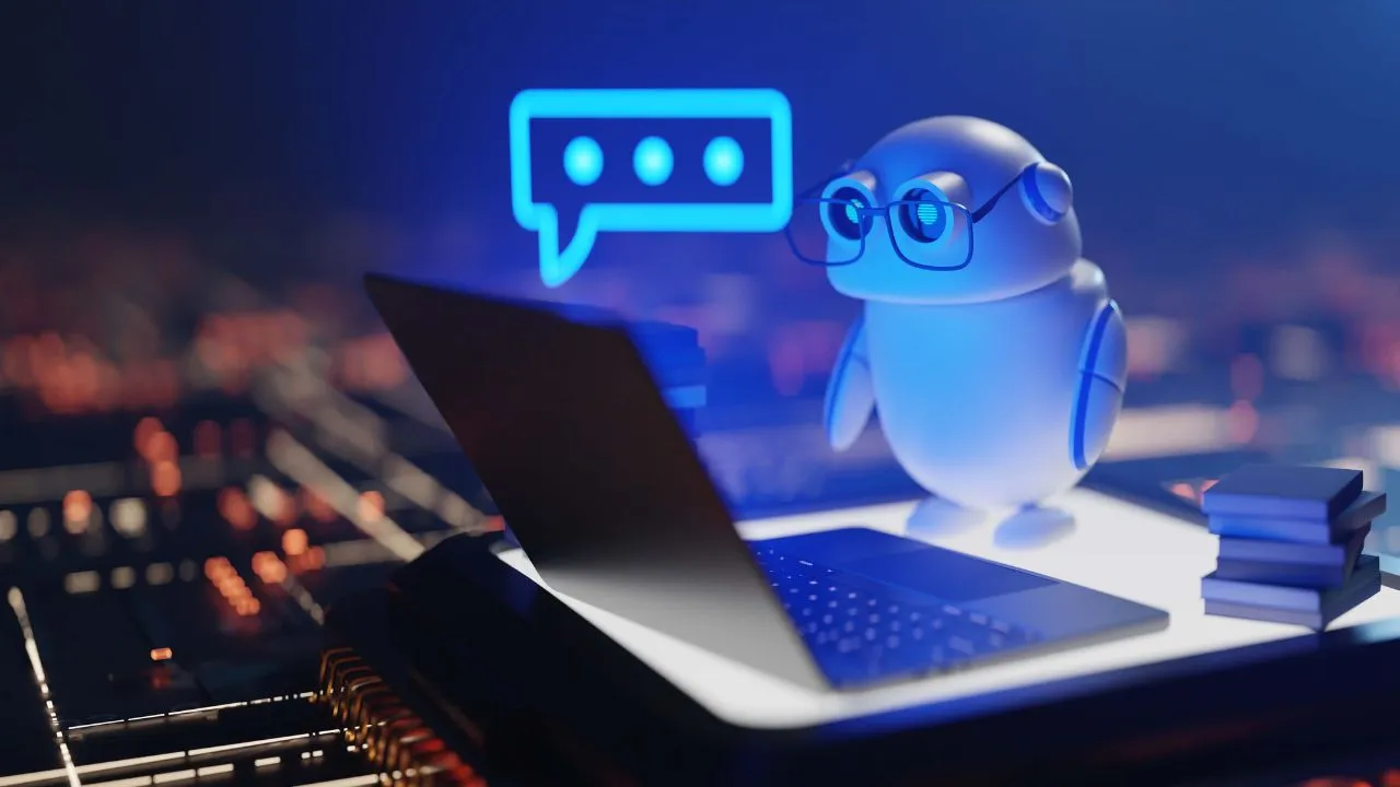 A 3D-rendered white robot wearing glasses sits at a laptop with a glowing blue speech bubble above its head.