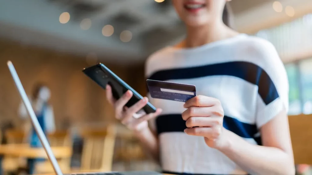 Close-up of a person holding a credit card and a smartphone, ready to make an online payment.