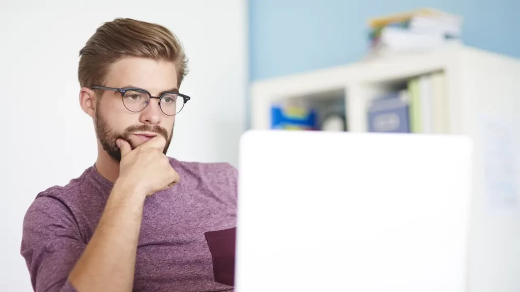 A man thinking while on his laptop.