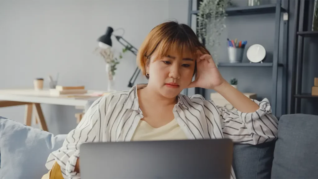 A woman thinking about something on her laptop.