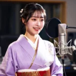 A woman in a purple kimono smiling while speaking into a professional studio microphone.