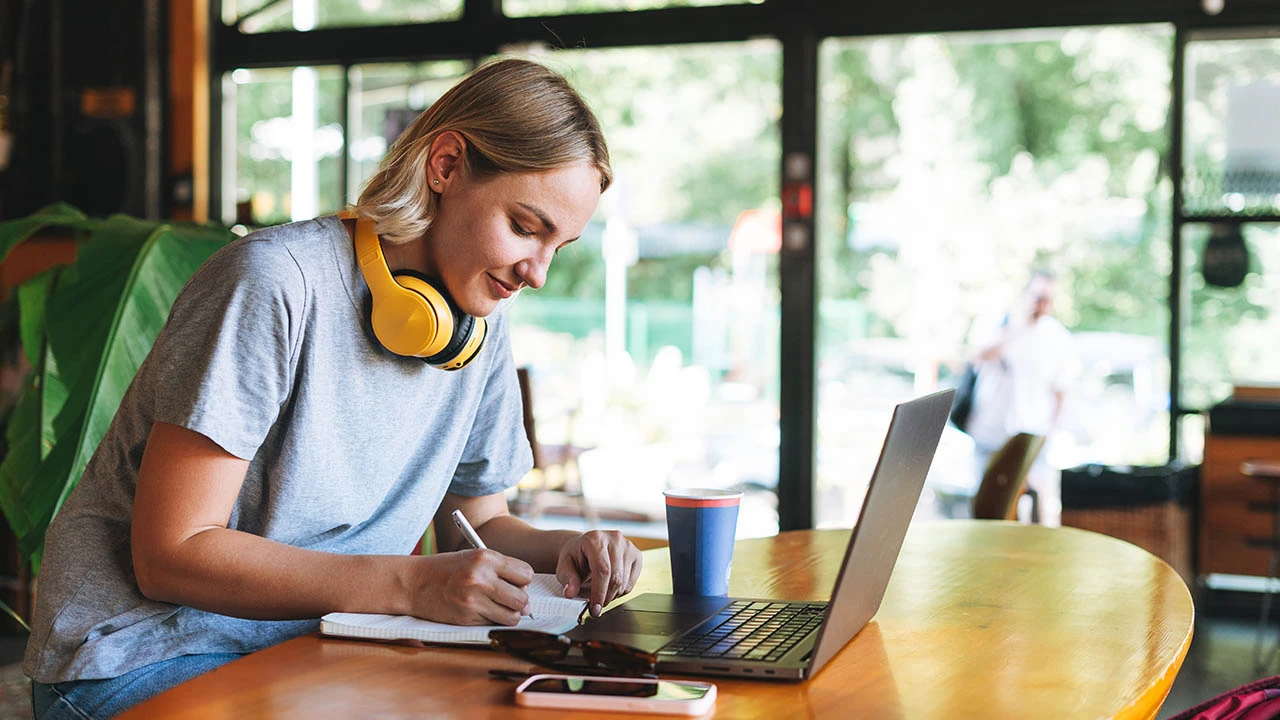Lesson sample: onboarding a new employee — A learner writes notes beside a laptop.